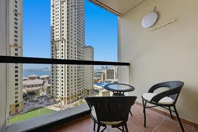 a balcony with a table and chairs and a large window at 3 Bed Spacious JBR Modern Living Holiday Home in Dubai