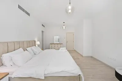 a white bedroom with a large bed with white sheets at 3 Bed Spacious JBR Modern Living Holiday Home in Dubai