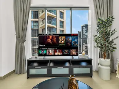 a living room with a flat screen tv on a entertainment center at Downtown 1BR Pool with Burj Khalifa View Near Dubai Mall in Dubai