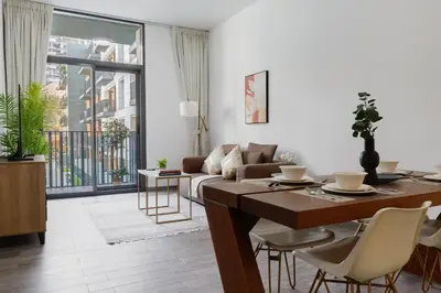a living room with a table and a couch at Belgravia Square, JVC - 1 Bedroom Apartment - Allsopp & Allsopp in Dubai