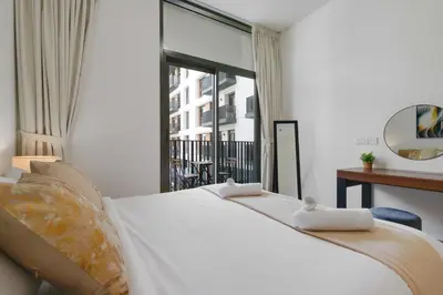 a bedroom with a large white bed and a window at Belgravia Square, JVC - 1 Bedroom Apartment - Allsopp & Allsopp in Dubai