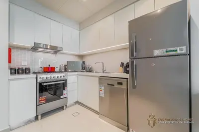 a kitchen with white cabinets and a stainless steel refrigerator at Modern 1BR Apartment in Dubai Creek Harbour by DVR Vacation Homes in Dubai