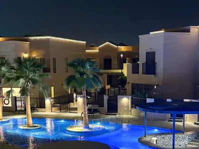 a building with palm trees in a courtyard at night at Luxury 3BR Villa with Pool View & Modern Comfort in Dubai