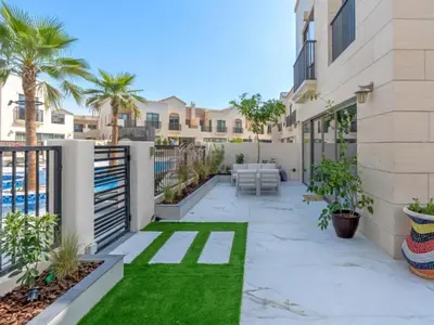 a courtyard with a patio with grass and palm trees at Luxury 3BR Villa with Pool View & Modern Comfort in Dubai