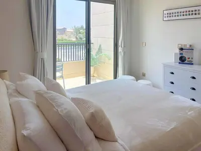 a bedroom with a large white bed with a balcony at Luxury 3BR Villa with Pool View & Modern Comfort in Dubai