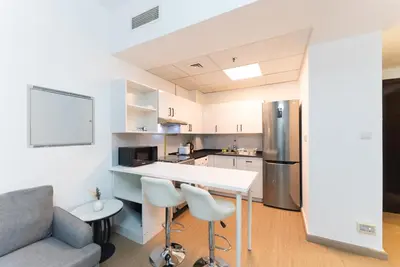 a kitchen with a table and chairs and a refrigerator at Escape24 Spacious 1BR with Pool View, JVC in Dubai