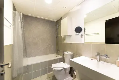 a bathroom with a toilet and a sink and a tub at Escape24 Spacious 1BR with Pool View, JVC in Dubai