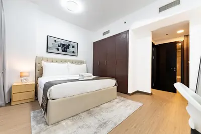 a bedroom with a large bed and a brown cabinet at Escape24 Spacious 1BR with Pool View, JVC in Dubai