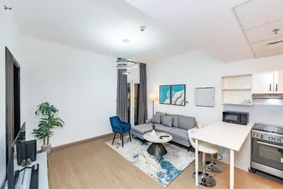 a living room with a couch and a table at Escape24 Spacious 1BR with Pool View, JVC in Dubai