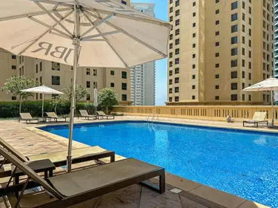 a swimming pool with an umbrella and chairs and a table at Tiramisu - Luxurious 2 BR Apartment- JBR Beach in Dubai