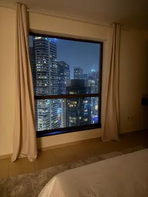 a bedroom window with a view of a city at night at Tiramisu - Luxurious 2 BR Apartment- JBR Beach in Dubai
