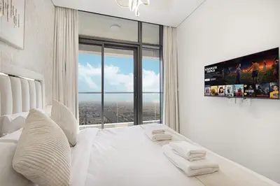 a bedroom with a white bed with a large window at Skyline Retreat, 2BDR Ensuite Comfort, City View in Dubai
