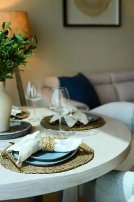 a table with two plates and wine glasses on it at Coastal 1BR with Balcony and Marina Ain Dubai Bluewaters Views in Dubai