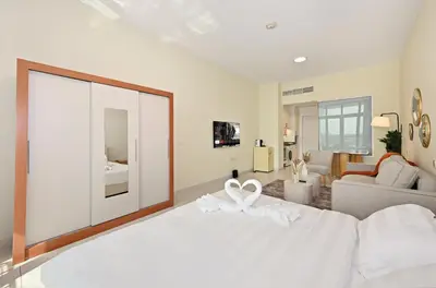 a bedroom with a white bed with a white bow on it at Amazing Views of Palm & Dubai Eye Stylish Studio in Dubai