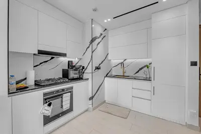 a kitchen with white cabinets and a stove at Modern Luxe | Heart of Dubai | Trillionaire Living in Dubai