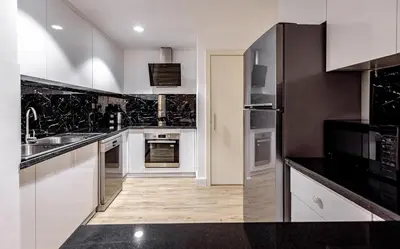 a kitchen with white cabinets and black appliances at Stylish 2-Bedroom Apartment with Marina View JBR in Dubai