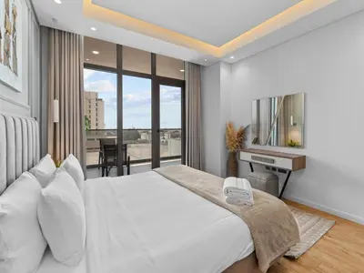 a bedroom with a large white bed and a desk at Convenient City Apartment Near Metro & Downtown in Dubai