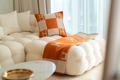 a white couch with orange and white pillows on it at Palace Beachfront Dubai Harbour in Dubai