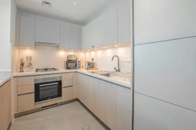 a large kitchen with white cabinets and appliances at Modern Stay at The Crest Tower Near Meydan with Pool and Sauna in Dubai