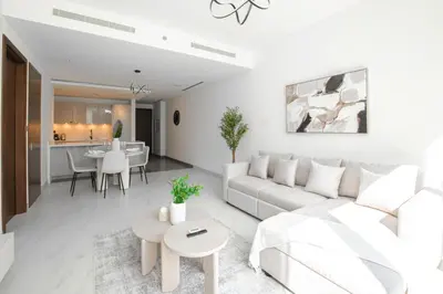 a white living room with a couch and a table at Modern Stay at The Crest Tower Near Meydan with Pool and Sauna in Dubai