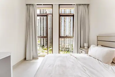 a white bedroom with a bed and large windows at Creek crescent in Dubai