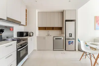 a white kitchen with white appliances and a table at Creek crescent in Dubai