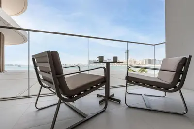 two chairs and a table on a balcony with a view at Beachfront Luxe 1BR Grand Bleu with Private Beach & Sea View in Dubai