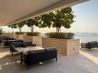 a patio with tables and chairs and a view of the water at Beachfront Luxe 1BR Grand Bleu with Private Beach & Sea View in Dubai
