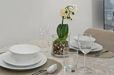 a table with plates and glasses and a vase with a flower at Deluxe Studio for 2 in Peninsula One, Business Bay in Dubai
