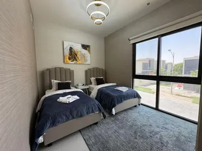 a bedroom with two beds and a large window at Luxury Smart Home Villa Damac Hills 2 3BR Ensuite in Dubai