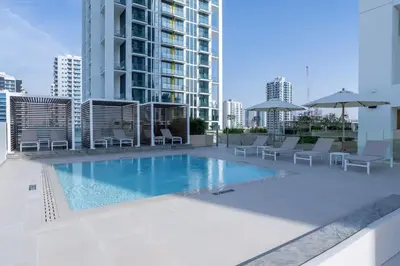 a swimming pool with chairs and umbrellas on a building at Warm Modern 2BR Retreat with Private Pool in JVC! in Dubai