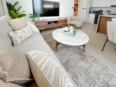 a living room with a couch and a table at Warm Modern 2BR Retreat with Private Pool in JVC! in Dubai
