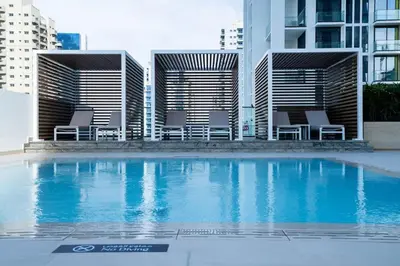 a swimming pool with chairs in front of a building at Warm Modern 2BR Retreat with Private Pool in JVC! in Dubai
