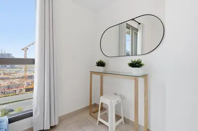 a mirror on a wall next to a table with a stool at Town Square Zahra 2B - 2 Bedroom Apartment - Allsopp & Allsopp in Dubai