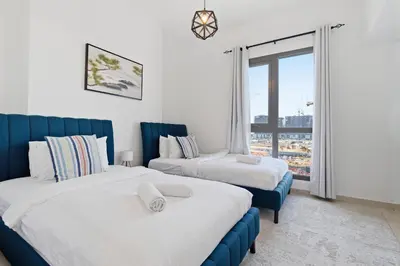 a hotel room with two beds and a window at Town Square Zahra 2B - 2 Bedroom Apartment - Allsopp & Allsopp in Dubai