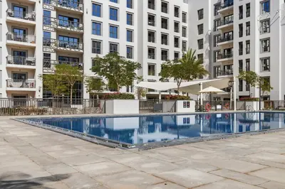 a swimming pool in front of a large apartment building at Town Square Zahra 2B - 2 Bedroom Apartment - Allsopp & Allsopp in Dubai