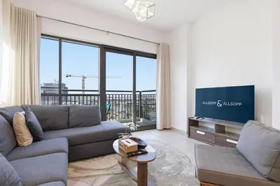 a living room with a couch and a flat screen tv at Town Square Zahra 2B - 2 Bedroom Apartment - Allsopp & Allsopp in Dubai