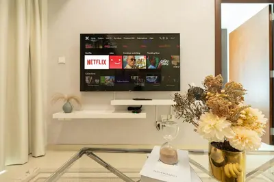 a living room with a tv and a table with flowers at Dubai Luxury 2BR - Pool, Gym & Burj Khalifa View in Dubai