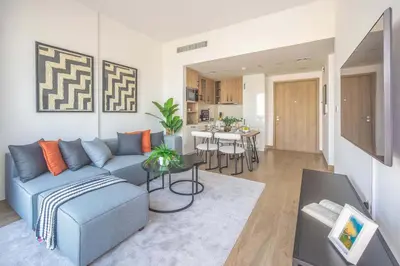 a living room with a blue couch and a kitchen at Frank Porter - Liva, Townsquare in Dubai