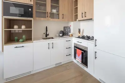 a white kitchen with white cabinets and a stove at Frank Porter - Liva, Townsquare in Dubai