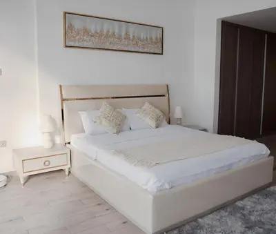 a bedroom with a white bed and a night stand at Elegant Studio with Pool & Gym in JVC in Dubai
