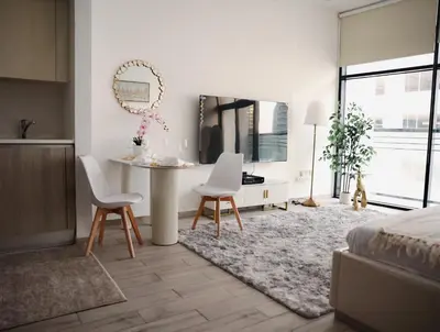 a living room with a table and two chairs at Elegant Studio with Pool & Gym in JVC in Dubai