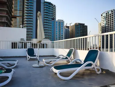 three chairs and an umbrella on a balcony with buildings at Elegant Studio with Pool & Gym in JVC in Dubai