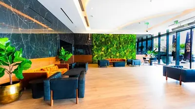a lobby with couches and plants on the wall at The Nobles Tower High Floor with Elegant City View in Dubai