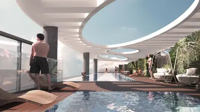 a man standing next to a swimming pool in a building at Brand New 1BR Apartment in JVC in Dubai