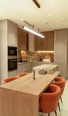 a kitchen with a large wooden table with orange chairs at Brand New 1BR Apartment in JVC in Dubai
