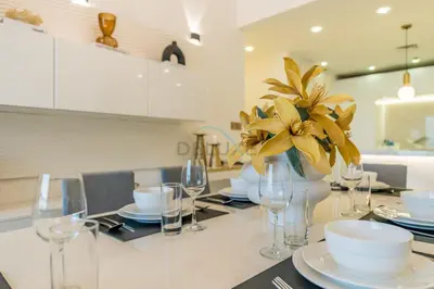 a table with glasses and a vase with flowers on it at Panoramic Sea and Canal Views from High-Floor 2BR, Steps from Tram and Marina Beach, Shams 2, JBR by Dekuxe Holiday Homes in Dubai