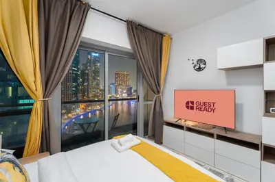 a bedroom with a bed and a large window at GuestReady - Cozy Studio | Pool & Gym | Canal view in Dubai