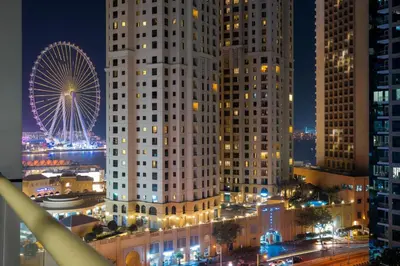 a city with tall buildings and a ferris wheel at night at GuestReady - Cozy Studio | Pool & Gym | Canal view in Dubai