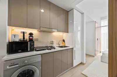a kitchen with a washing machine and a microwave at Elite Escape - Getaway in Azizi Riviera 29 in Dubai